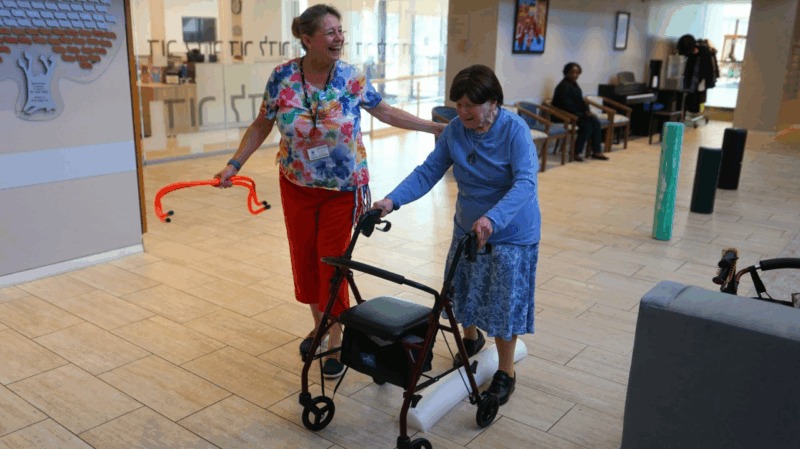 Two women enjoying mobility assistance in a hallway.