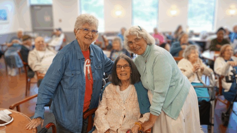 Three smiling women pose together in a social setting.