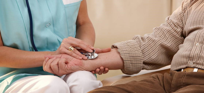 Nurse checking a patient's pulse with a stethoscope.