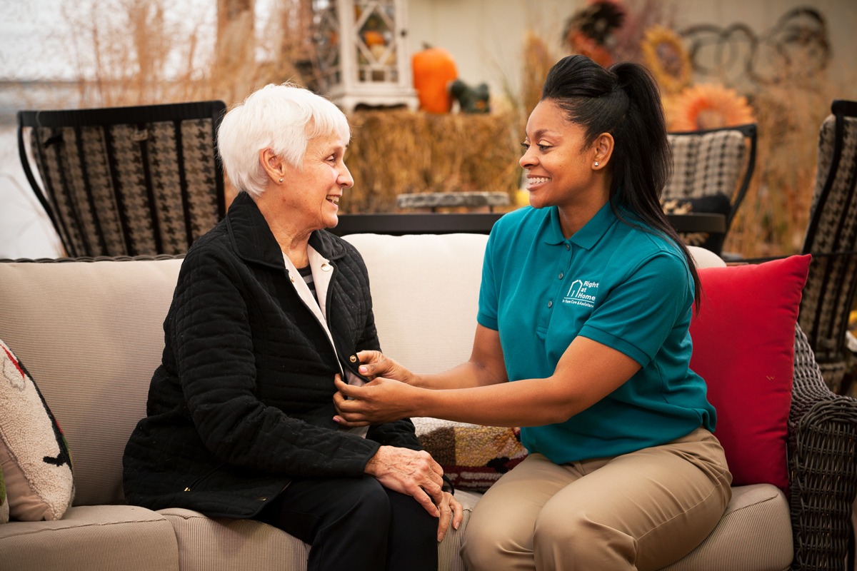 Caregiver and senior woman sharing a warm conversation indoors.